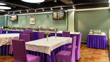 Un salón de conferencias con mesas y sillas, una mesa de buffet y obras de arte en las paredes.