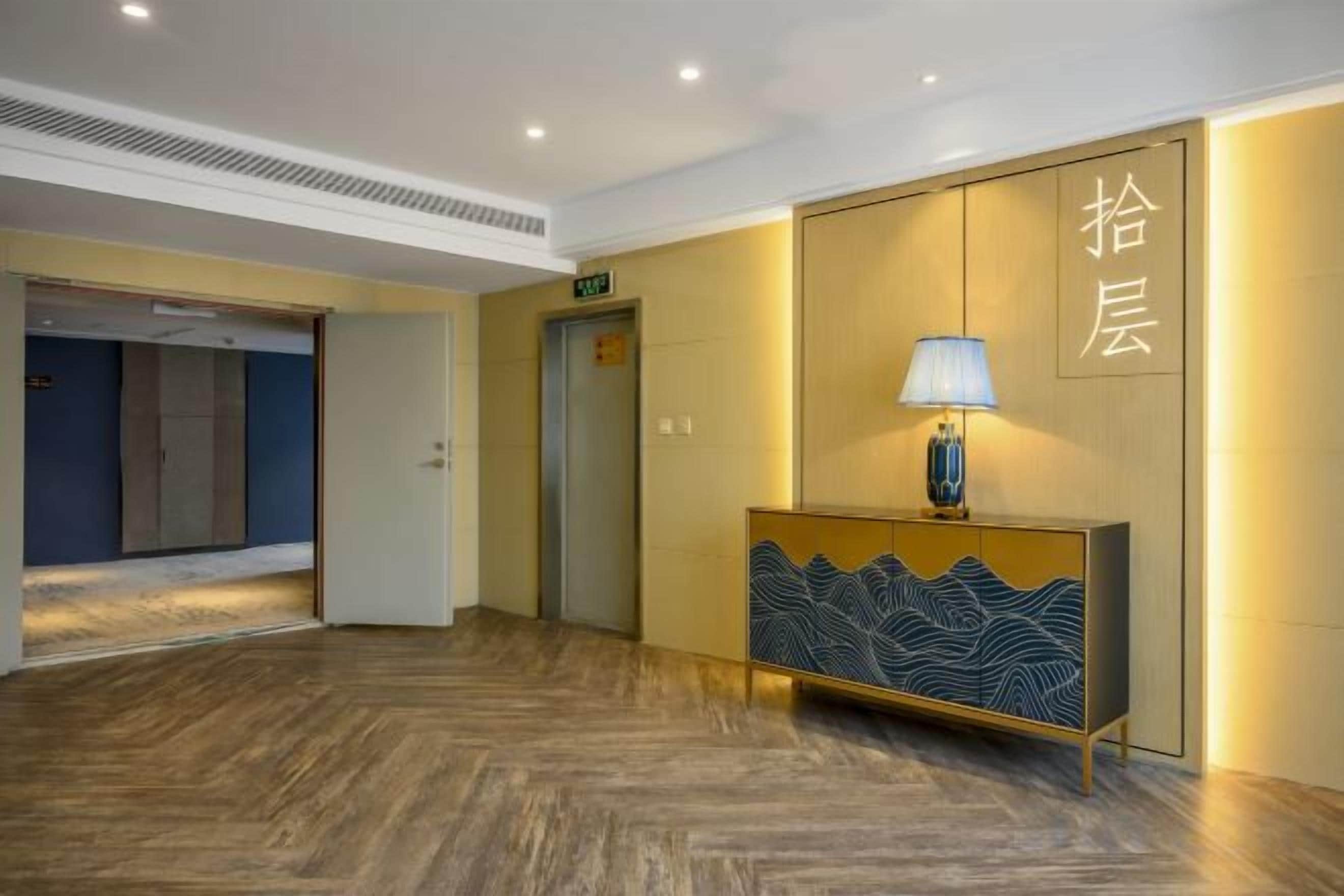 Un vestíbulo de hotel con un mostrador de recepción, un ascensor y un piso de madera.