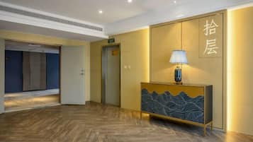 Un vestíbulo de hotel con un mostrador de recepción, un ascensor y un piso de madera.