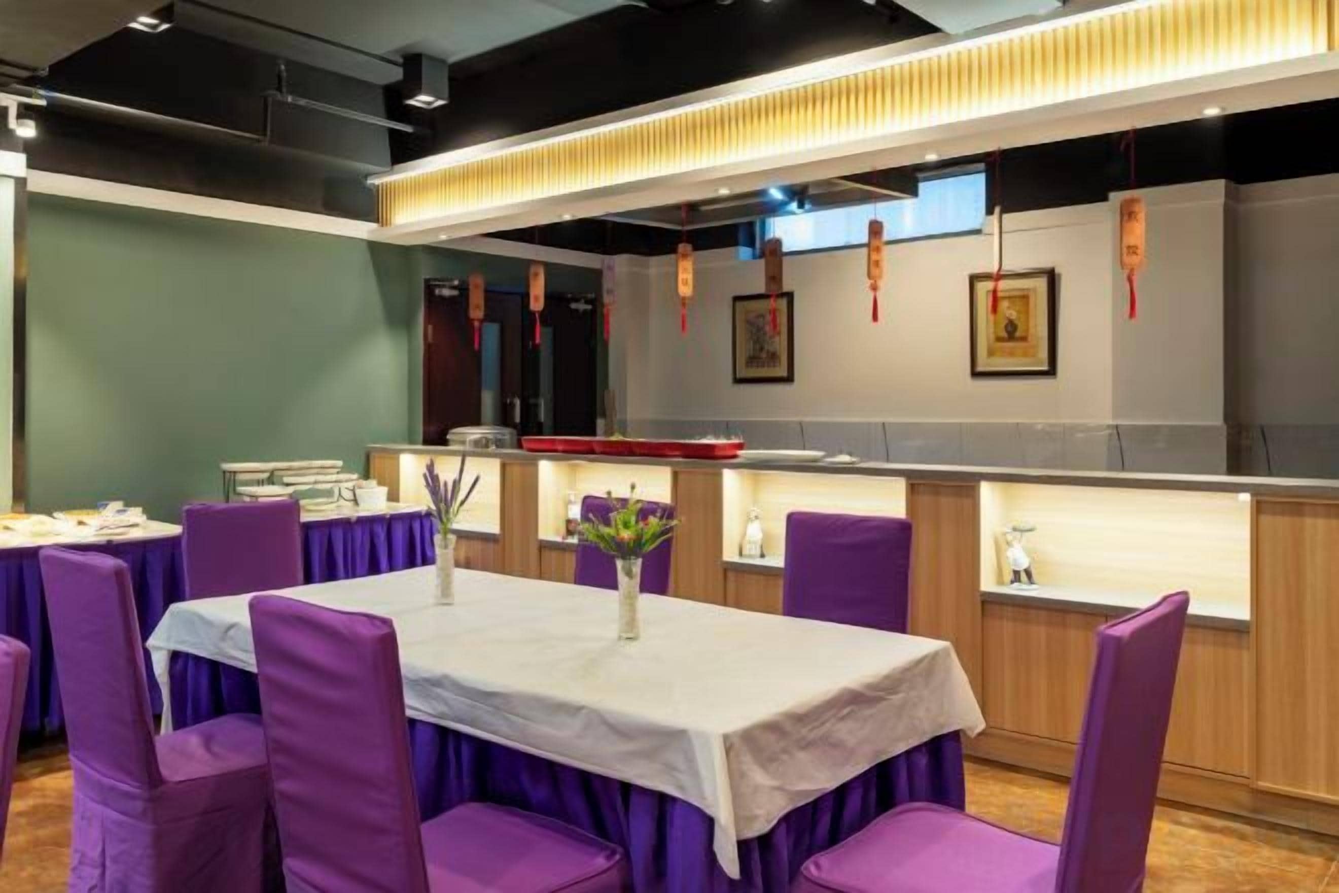Un'area pranzo con sedie e tavoli viola, un bancone con il menu e una parete con quadri.