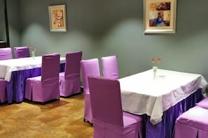 A dining area with tables and chairs, a wooden floor, and artwork on the walls. - Hai Tian Holiday Inn (Zhengzhou)