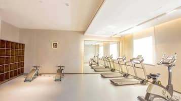 A gym with exercise equipment, a mirror, and a window.