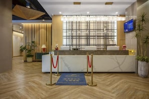 A hotel reception area with a marble counter, red ropes, and a large window. - Hai Tian Holiday Inn (Zhengzhou)