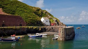 A coastal scene with a small white building, a stone wall, and boats docked at a pier. - 3 Stable Yard, Holiday Cottage St Davids, Sleeps 6, 3 bedrooms,  bathrooms (St Davids)