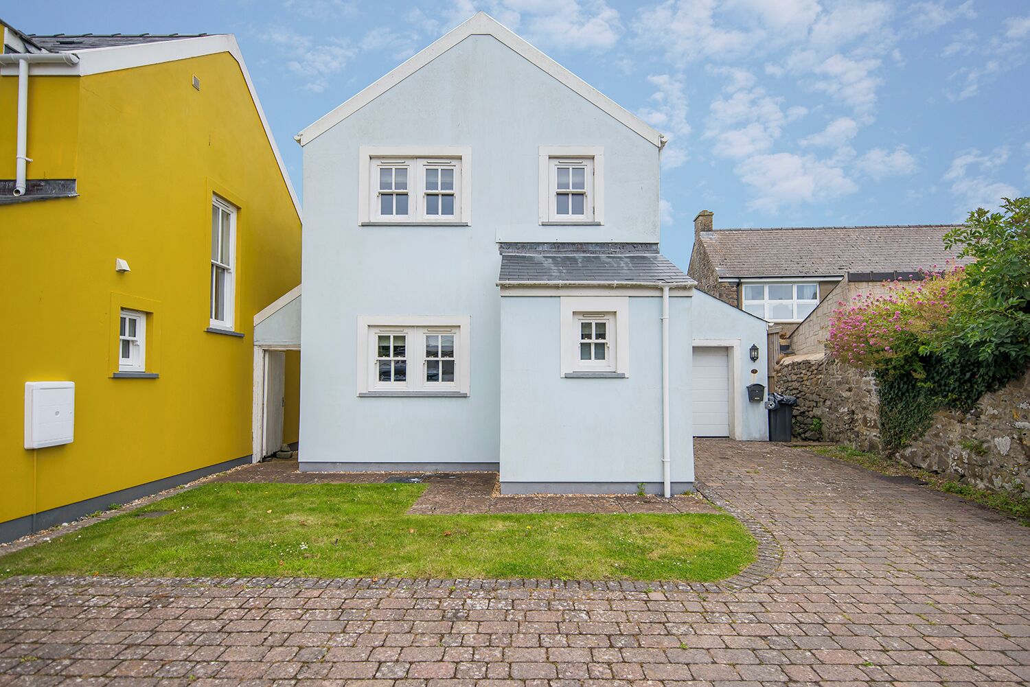 A two-story house with a white exterior and a yellow side building.