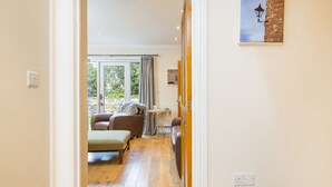 A hallway leading to a living area with a sofa, a table, and a view of the outdoors. - 3 Stable Yard, Holiday Cottage St Davids, Sleeps 6, 3 bedrooms,  bathrooms (St Davids)