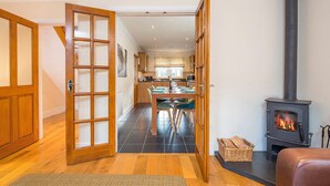 A cozy interior with a dining area, a fireplace, and a wooden door. - 3 Stable Yard, Holiday Cottage St Davids, Sleeps 6, 3 bedrooms,  bathrooms (St Davids)