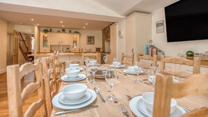 A dining area with a wooden table set for a meal, surrounded by wooden chairs. - 3 The Glen, holiday property Saundersfoot, Sleeps 8, 4 bedrooms,  bathrooms (Saundersfoot)
