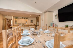 A dining area with a wooden table set for a meal, surrounded by wooden chairs.