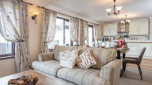 A cozy living room with a striped sofa, a wooden coffee table, and a dining area with a kitchen in the background.