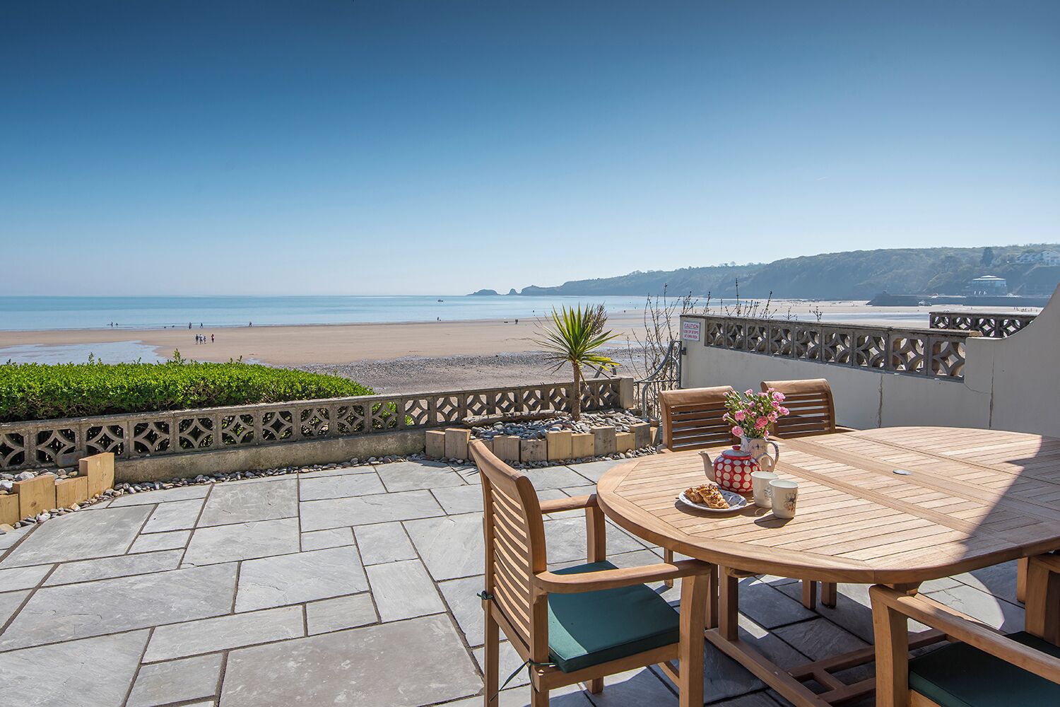 A patio with a table and chairs overlooking a beach.
