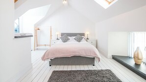 A bedroom with a sloped ceiling, a skylight, a bed with a pink blanket, two bedside tables with lamps, and a large window. - 7 Prendergast, Holiday Cottage Solva , Sleeps 6, 4 bedrooms,  bathrooms (Haverfordwest)