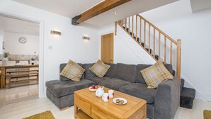 A modern living room with a grey sofa, wooden coffee table, and a staircase with wooden railings. - 7 Prendergast, Holiday Cottage Solva , Sleeps 6, 4 bedrooms,  bathrooms (Haverfordwest)