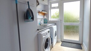 Une buanderie équipée d’un lave-linge, d’un sèche-linge et d’un balai.