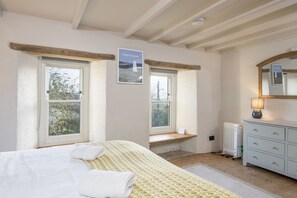 A bedroom with a bed, two windows, a dresser, a mirror, and a sign reading "PORTHGAIN".