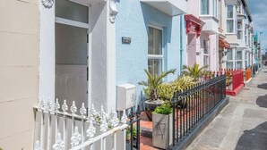 A row of colorful terraced houses with white railings and a small garden area. - Anvil House, Holiday Home Tenby, Sleeps 8, 4 bedrooms,  bathrooms (Tenby)