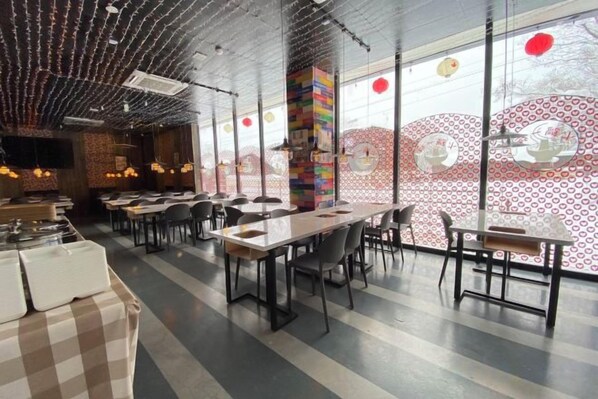 Un restaurante con techos altos, ventanas grandes y una decoración interior moderna.