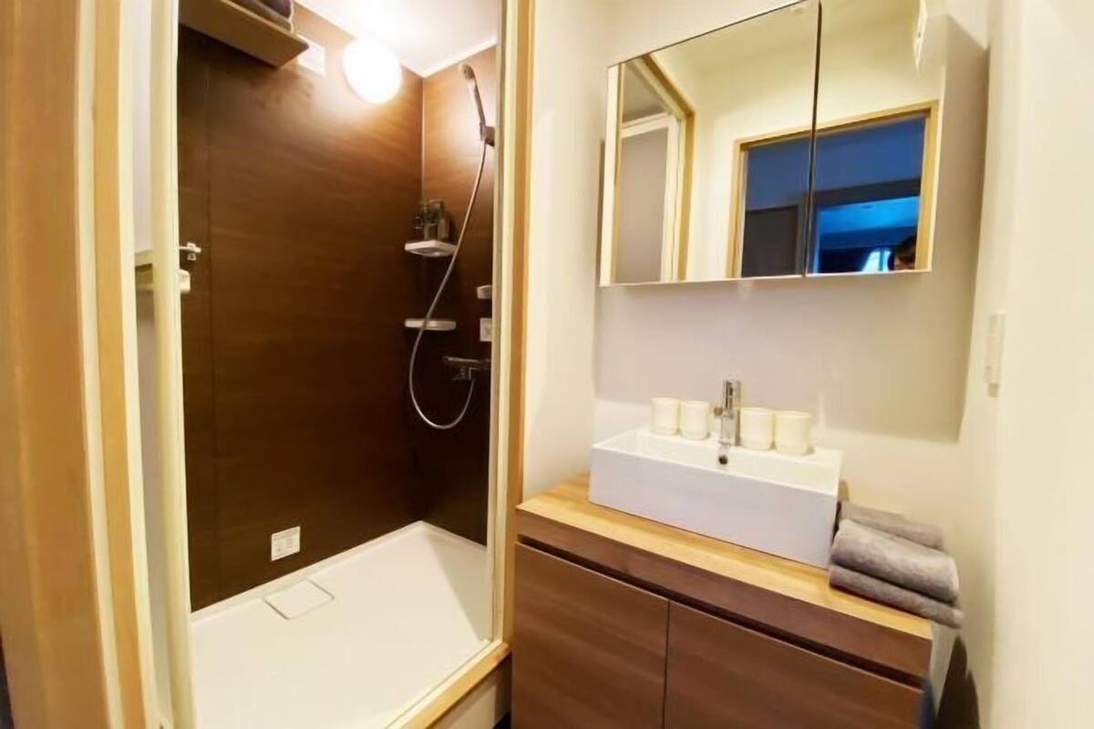 Een moderne badkamer met een inloopdouche, een wastafel met spiegel en een wasbak.