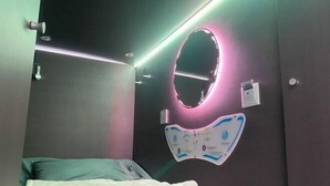 Un dormitorio con una cama, un espejo en la pared y un cartel mural.