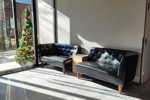 Una habitación moderna con un sofá de cuero negro, una mesita de madera y un árbol de Navidad.