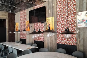 A restaurant interior with a long table, multiple chairs, hanging pendant lights, and a patterned wall. - Q Fox Black Diamond Hotel (Kutchan)