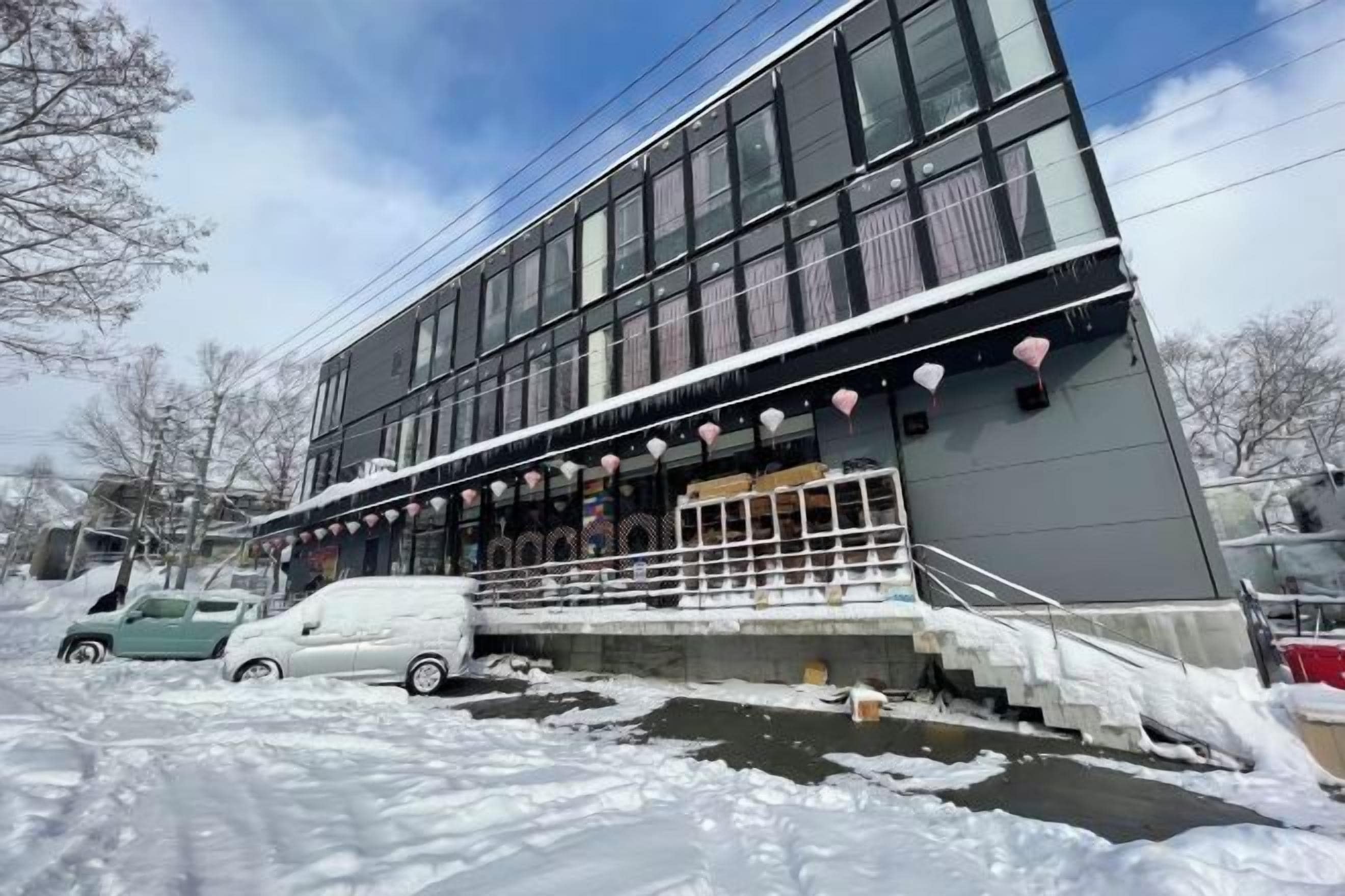A modern building with a flat roof, large windows, and a covered entrance area with steps.