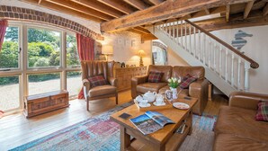 A cozy living room with leather furniture, a wooden coffee table, and a staircase. - Arch Barn, Holiday Cottage St Twynnells, Nr Bosherston | Stackpole, Sleeps 6, 3 bedrooms,  bathrooms (PEMBROKE)