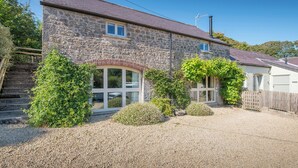 A stone house with a gravel driveway, a wooden fence, and a small garden area. - Arch Barn, Holiday Cottage St Twynnells, Nr Bosherston | Stackpole, Sleeps 6, 3 bedrooms,  bathrooms (PEMBROKE)
