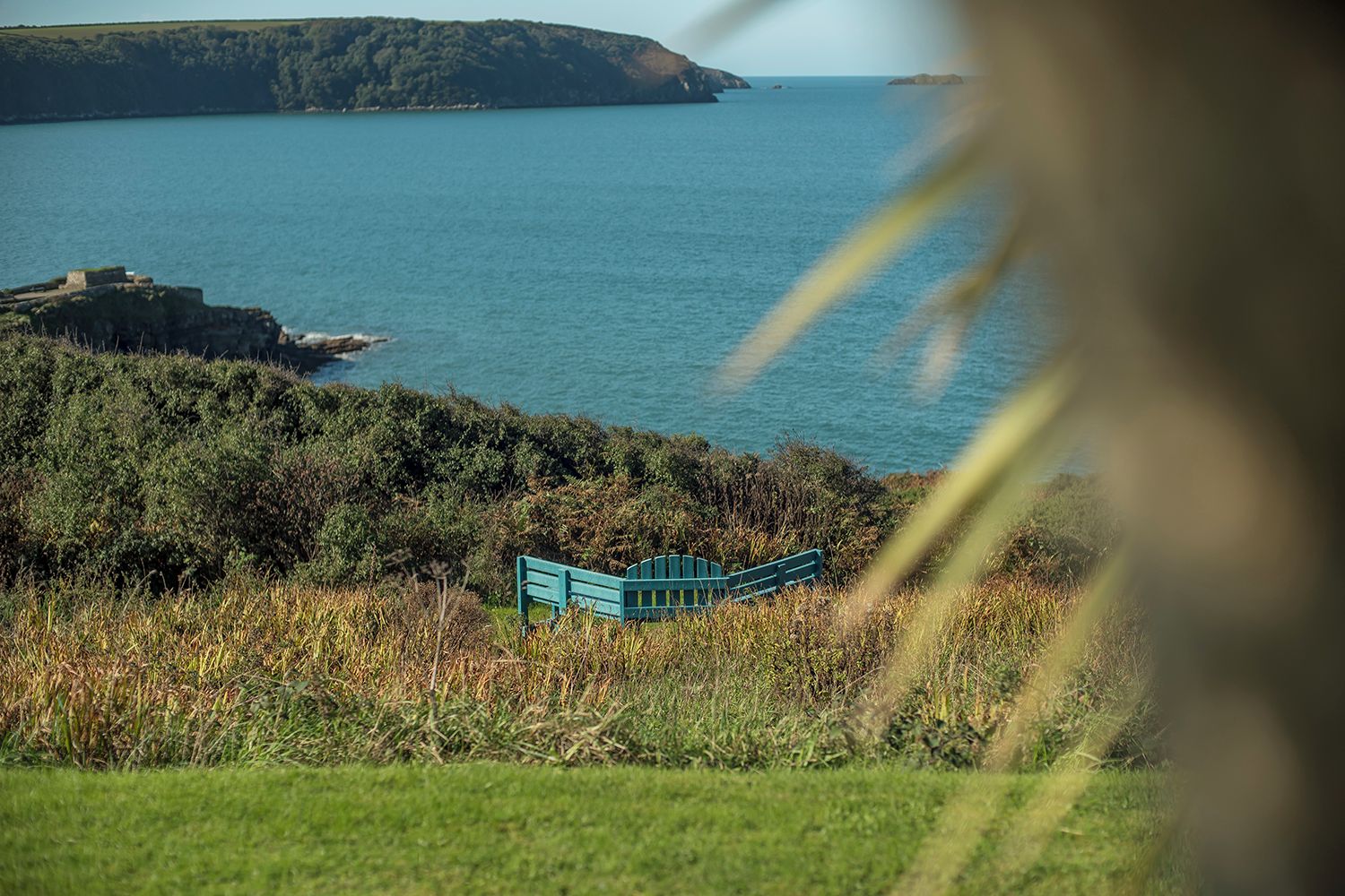 A bench overlooking a body of water with a distant landmass.