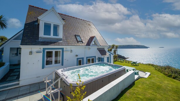 Une maison avec une piscine, une terrasse et une vue sur la mer.