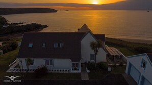 Une maison située sur la côte, offrant une vue sur le coucher de soleil sur la mer.