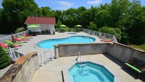 Un espace piscine comprenant deux piscines, des chaises longues et des parasols.