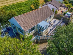 Ein zweistöckiges Haus mit einem Ziegeldach, einem Balkon und einer kleinen Terrasse.