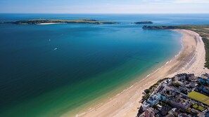 An aerial view of a coastal town with a sandy beach, clear blue waters, and a mix of residential and commercial buildings. - Black Hall Cottage, Holiday Cottage Amroth, Sleeps 6, 3 bedrooms,  bathrooms (Amroth)