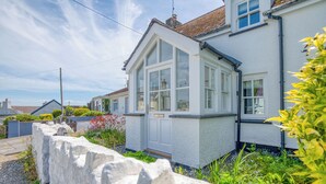 A white house with a large bay window, a stone wall, and a garden with various plants and flowers. - Blackberry Cottage, Holiday Cottage Solva, Sleeps 4, 2 bedrooms,  bathrooms (Haverfordwest)