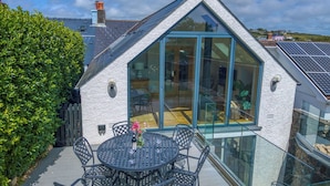 A modern house with a glass conservatory, a dining area with outdoor seating, and a solar panel on the roof. - Blackberry Cottage, Holiday Cottage Solva, Sleeps 4, 2 bedrooms,  bathrooms (Haverfordwest)
