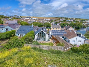 Een woonwijk met huizen, waarvan sommige zonnepanelen hebben, en een heldere lucht.