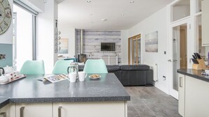 A modern kitchen with a central island, light-colored cabinets, and a grey tiled floor. - Brierbank, Holiday Property Tenby, Sleeps 10, 5 bedrooms,  bathrooms (Tenby)