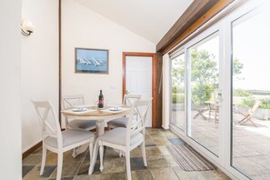 Un espace repas comprenant une table, des chaises et une porte donnant sur un patio extérieur.