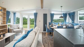 A modern living room with a sofa, chairs, a dining area, and a kitchen counter. - Brynteg, Holiday Cottage Bonville’s Court Country Park, Saundersfoot, Sleeps 6, 3 bedrooms,  bathrooms (Saundersfoot)