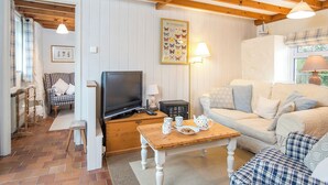 A cozy living room with a television, a wooden coffee table with cups and a teapot, a sofa, and a chair. - Bwthyn Bach, Holiday Cottage Trefin, Sleeps 2, 1 bedrooms,  bathrooms (Haverfordwest)