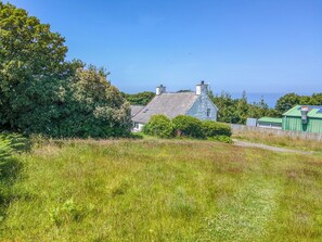 A house with a stone roof, surrounded by greenery and a clear sky. - Bwthyn Bach, Holiday Cottage Trefin, Sleeps 2, 1 bedrooms, bathrooms (Haverfordwest)