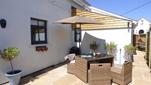 A patio area with a table and chairs, a wooden pergola, and potted plants. - Bwthyn Clyd, Holiday Cottage Keeston, Near Newgale, Sleeps 6, 3 bedrooms,  bathrooms (Haverfordwest)