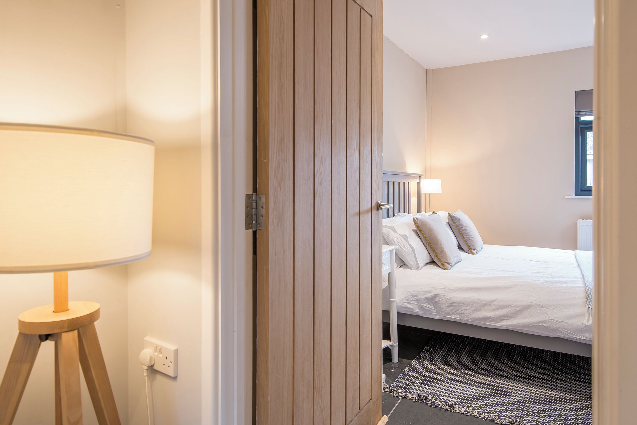 A bedroom with a bed, bedside lamps, a bedside table, and a power outlet.