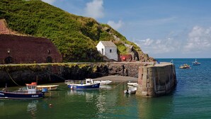 A coastal scene with a small white building, a stone wall, and boats docked at a pier. - 2 Caerau Isaf, Holiday Home Aberfelin Bay, Sleeps 4, 4 bedrooms,  bathrooms (Haverfordwest)