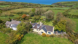 A coastal house with a sloped roof, surrounded by lush greenery and fields, with the sea in the background. - 2 Caerau Isaf, Holiday Home Aberfelin Bay, Sleeps 4, 4 bedrooms,  bathrooms (Haverfordwest)