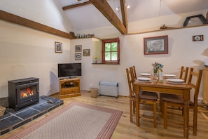 A cozy living room with a fireplace, a television, and a dining area with wooden furniture.