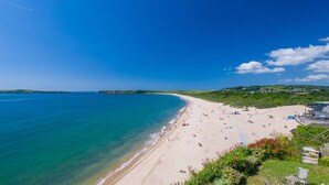 A beach with clear blue water, sandy shore, and a few buildings in the background. - Carew Cottage, Holiday Cottage Carew, Sleeps 4, 2 bedrooms,  bathrooms (Tenby)