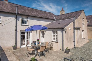 A patio with a table and chairs, a blue umbrella, and potted plants. - Carew Cottage, Holiday Cottage Carew, Sleeps 4, 2 bedrooms,  bathrooms (Tenby)