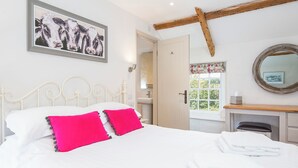 A bedroom with a bed, pillows, a painting, a mirror, and a window with curtains. - Carew Cottage, Holiday Cottage Carew, Sleeps 4, 2 bedrooms,  bathrooms (Tenby)